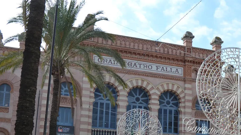 Fachada del Gran Teatro Falla de Cádiz engalanada con adornos luminosos de carnaval entre palmeras