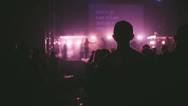 Siluetas del público ante el escenario iluminado de violeta de un concierto en sala