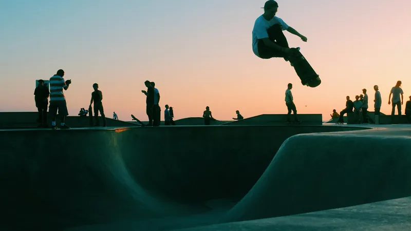Skater saltando en un skatepark al atardecer mientras otros miran