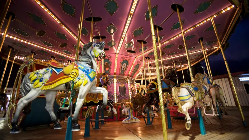 Caballitos de madera pintados de un carrusel iluminado con bombillas