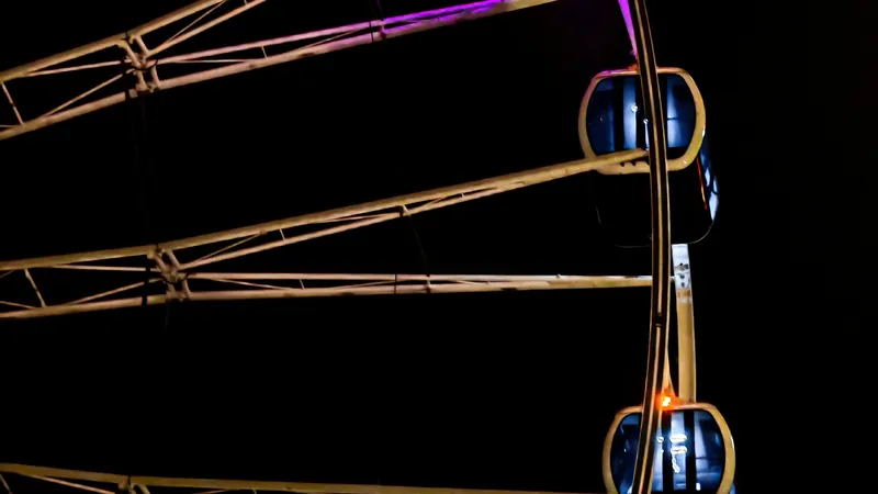 Noria iluminada con luces violetas en la noche