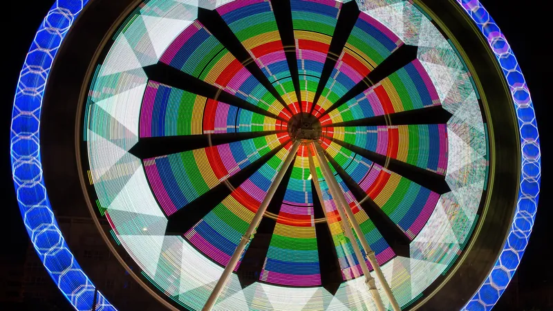 Noria de feria girando de noche con luces de colores en larga exposición