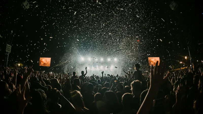 Público de un festival bajo una lluvia de confeti frente a un escenario iluminado