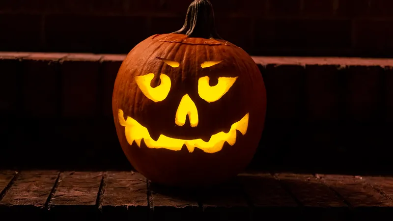 Calabaza de Halloween tallada e iluminada sobre unos escalones de ladrillo de noche