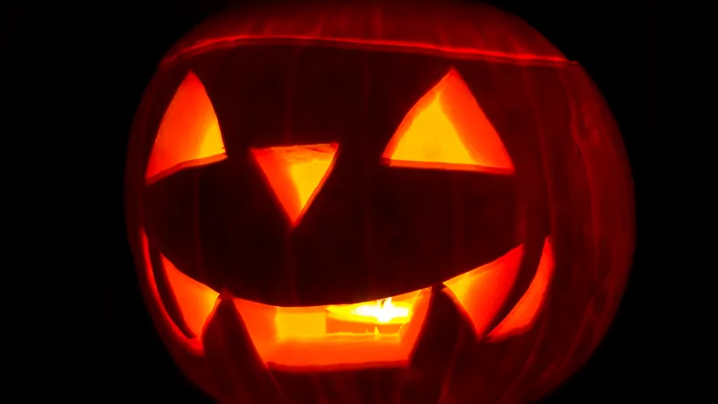 Calabaza de Halloween tallada con una sonrisa iluminada desde dentro en la oscuridad