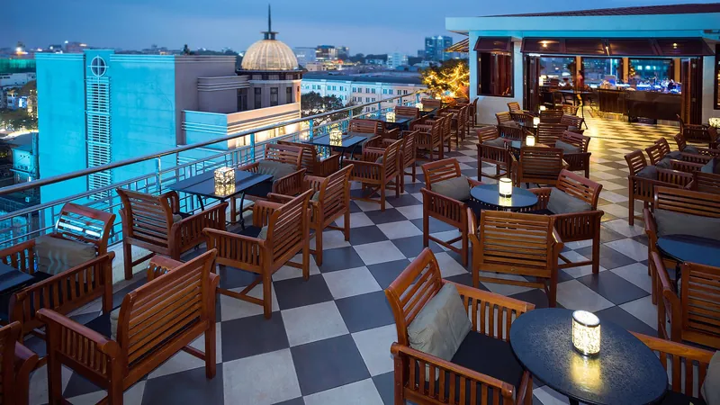 Terraza en una azotea al atardecer con butacas de madera, velas en las mesas y vistas a la ciudad