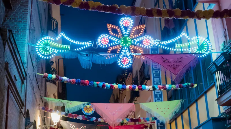 Calle estrecha engalanada con banderines y arcos de luces de colores en una noche de fiestas