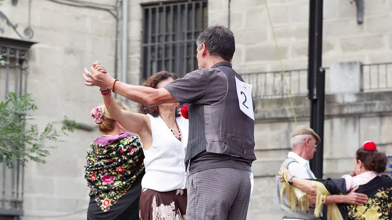 Parejas vestidas de chulapos bailando un pasodoble en el escenario de una verbena madrileña